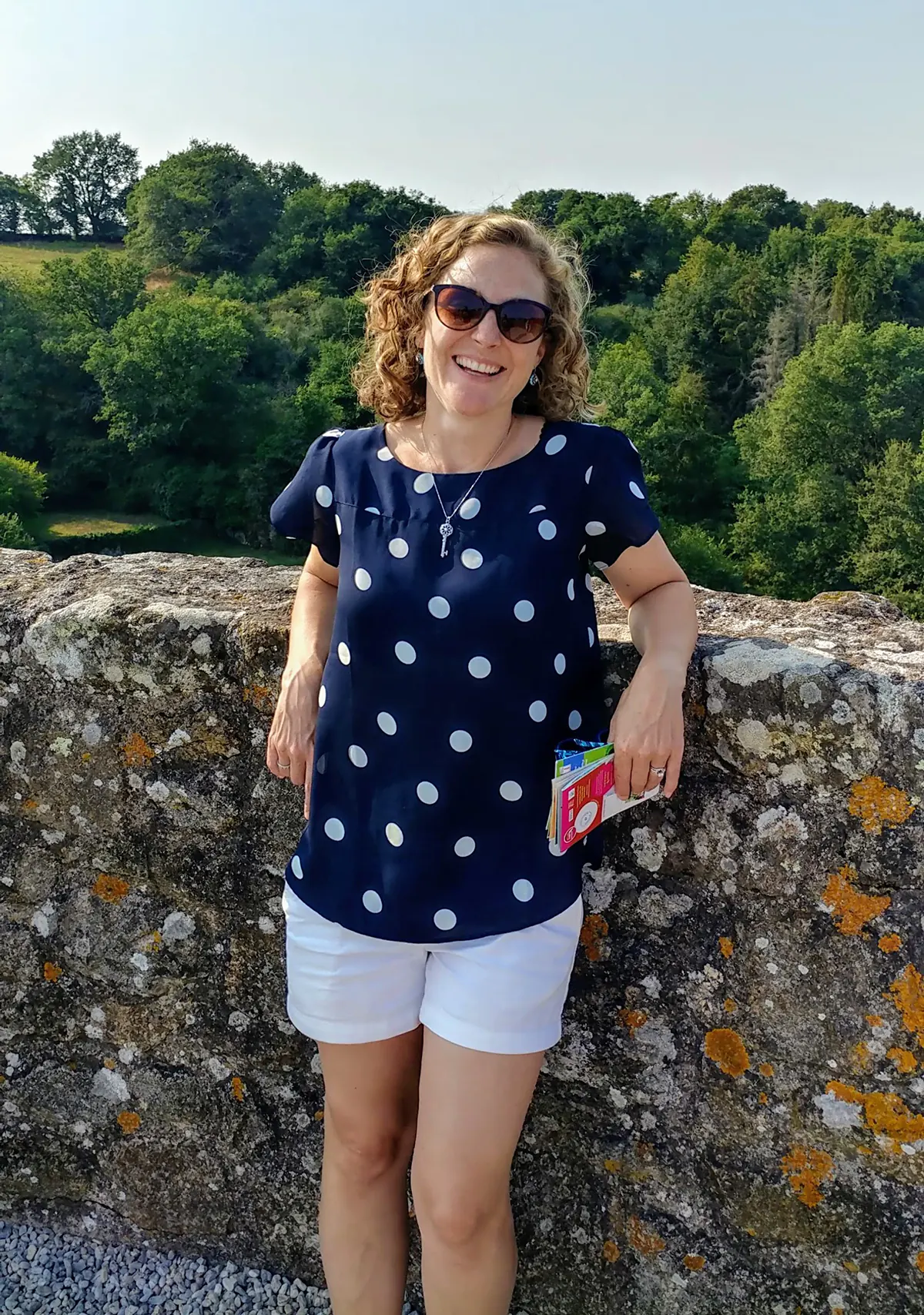 Invivyd employee Kim Chambert on vacation, standing against an old, lichen-covered wall